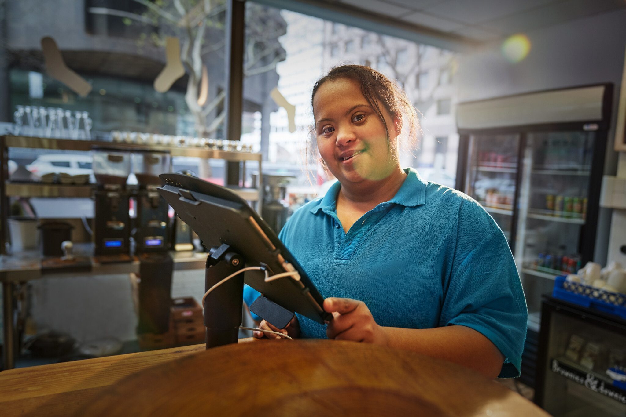 Portrait confident young woman with Down Syndrome working in caf
