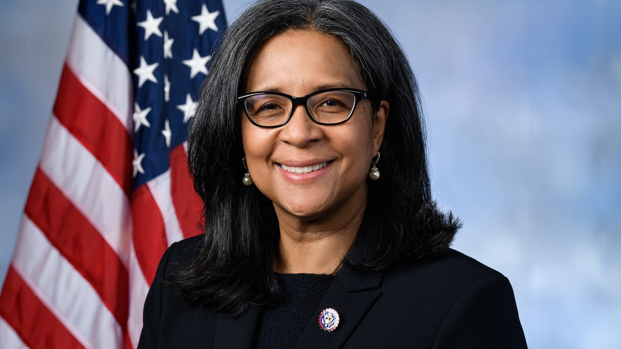 An official portrait of Marilyn Strickland smiling in front of an American flag.