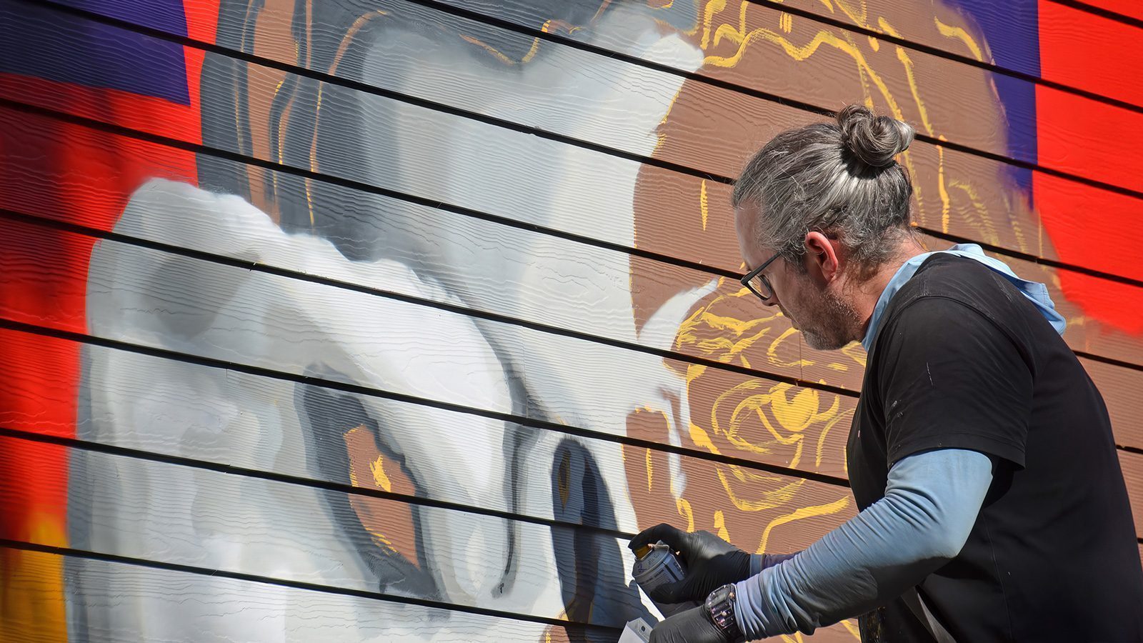 A close-up of artist Brady Black working on at mural at 415 Cedar St.