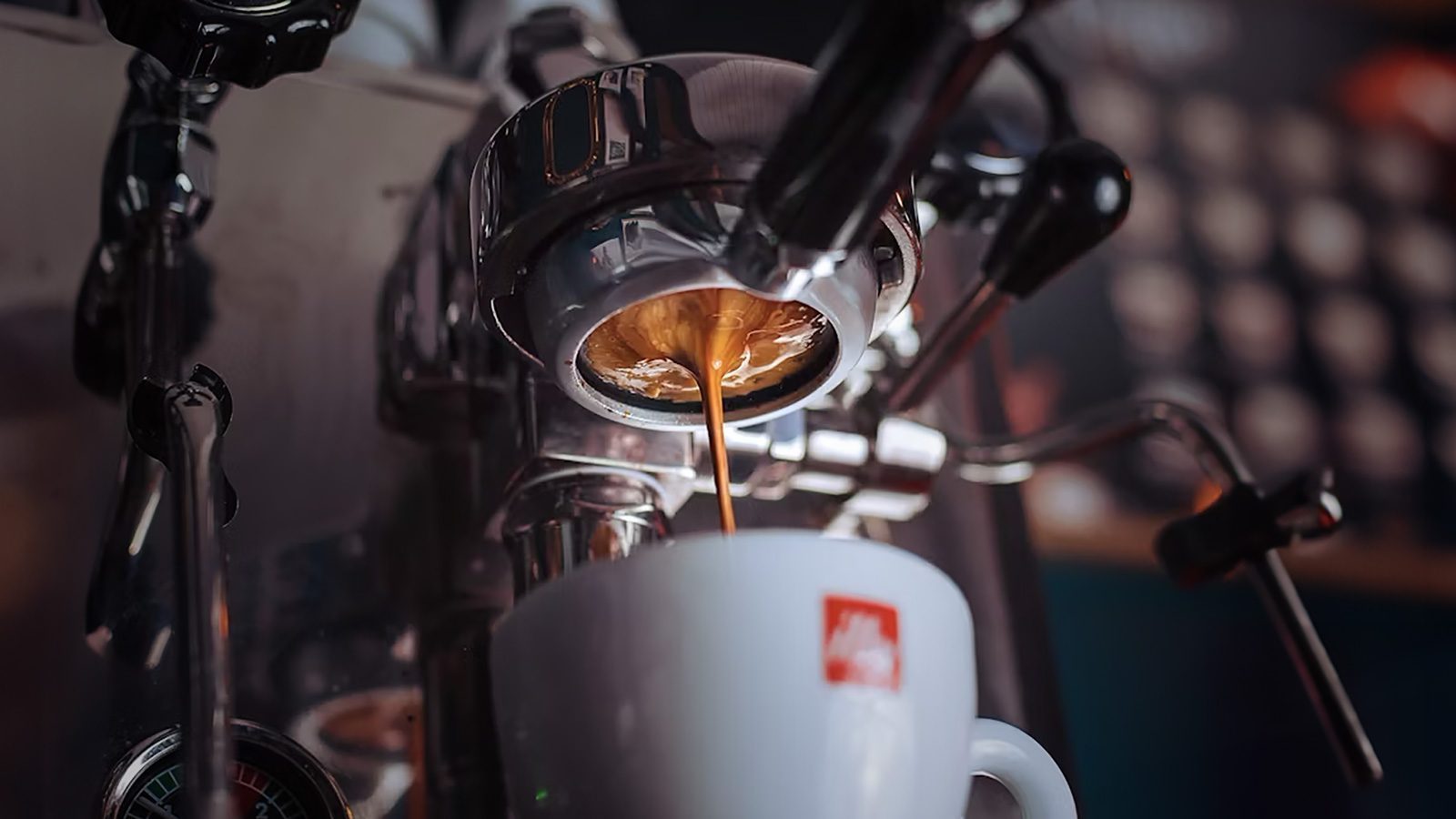 A close-up of an espresso machine pouring coffee into a white cup, inviting you to ponder your bean budget and how much to spend in coffee, especially when savoring the rich flavors reminiscent of those found in a cozy Seattle café.
