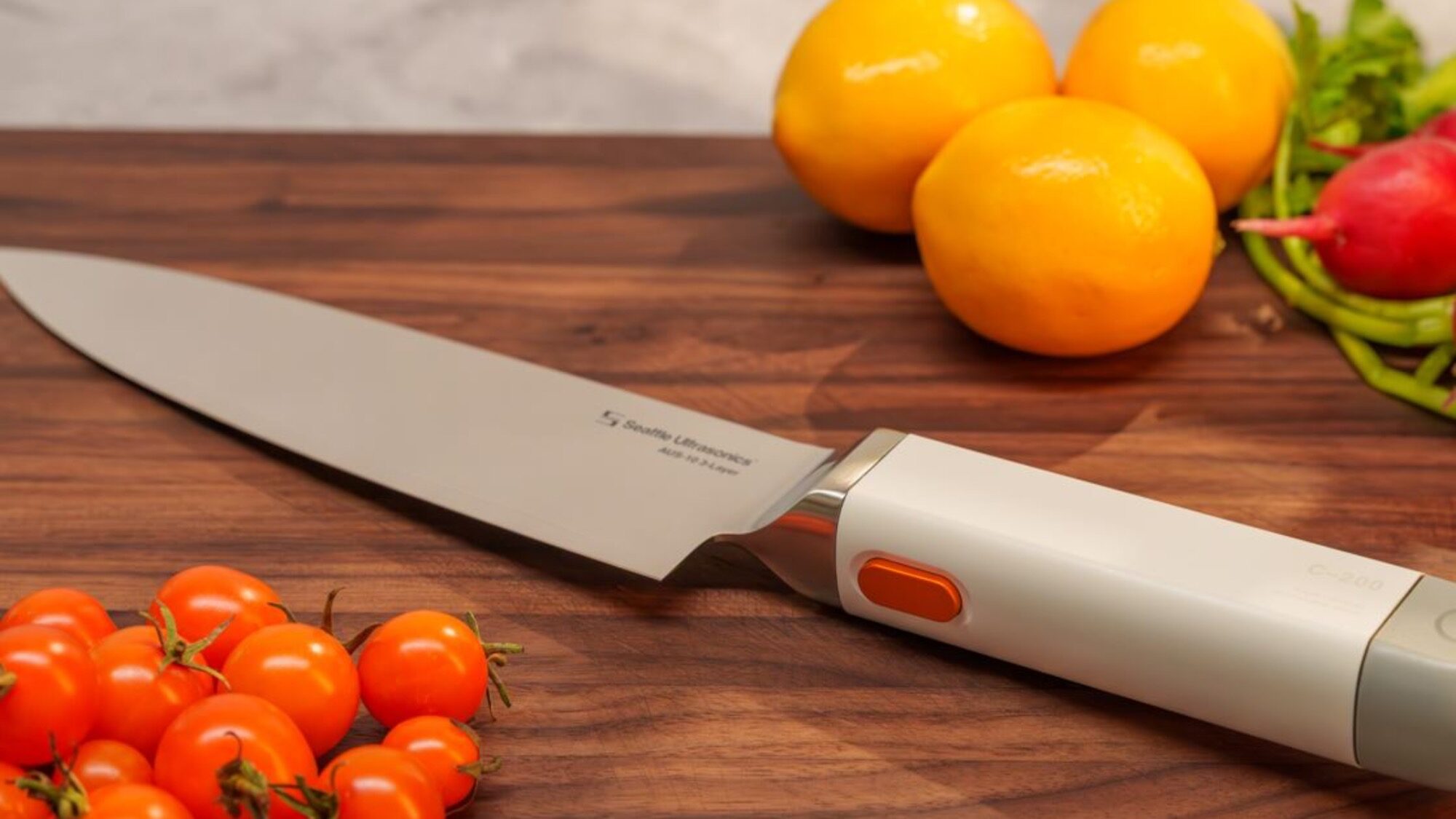 A chef’s knife on a wooden cutting board with cherry tomatoes, lemons, a radish, and green beans arranged around it—perfect for staying Ahead of the Cut in your kitchen prep.